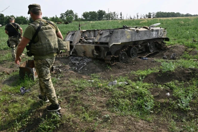 Un soldat ukrainien passe à proximité d'un char russe détruit dans un champ au sud de la ville de Mykolaiv (Ukraine) le 12 juin 2022 