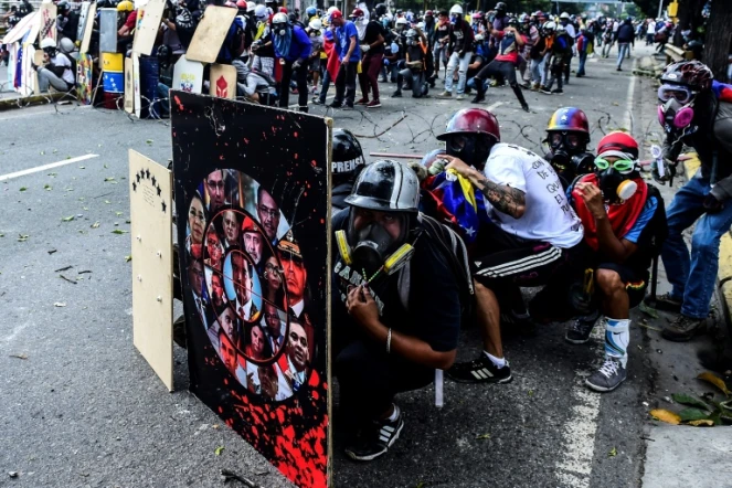 Des opposants au régime de Nicolas Maduro se protègent des assauts de la police derrière des boucliers de fortune, le 22 juillet 2017 à Caracas