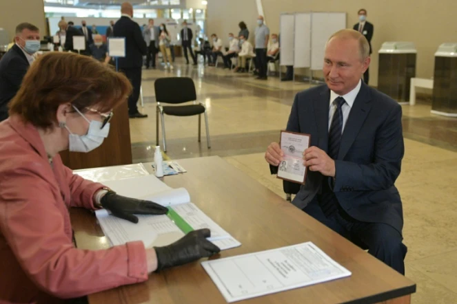 Le président russe Vladimir Poutine montre son passeport à un assesseur avant de voter à Moscou, le 1er juillet 2020.