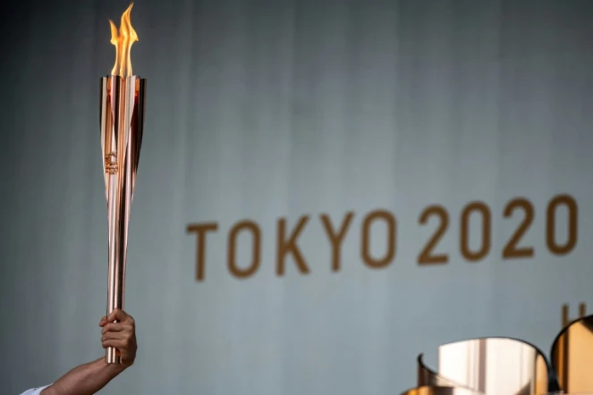 Un relayeur tient le flambeau olympique lors de la cérémonie d&rsquo;allumage de la flamme olympique au premier jour du relais à Machida, à l'ouest de Tokyo, le 9 juillet 2021
