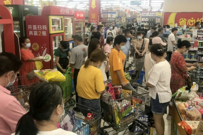 Das habitants de la ville chinoise de Wuhan font des achats dans un supermarché le 2 août 2021 