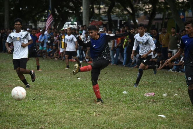 Un Rohingya de l'équipe Cheras Harimau frappe la balle tandis que des joueurs de Selangor (en blanc) le regardent lors d'un tournoi destiné aux réfugiés, à l'occasion des célébrations de la fin du ramadan en Malaisie, à Kuala Lumpur, le 18 juin 2018