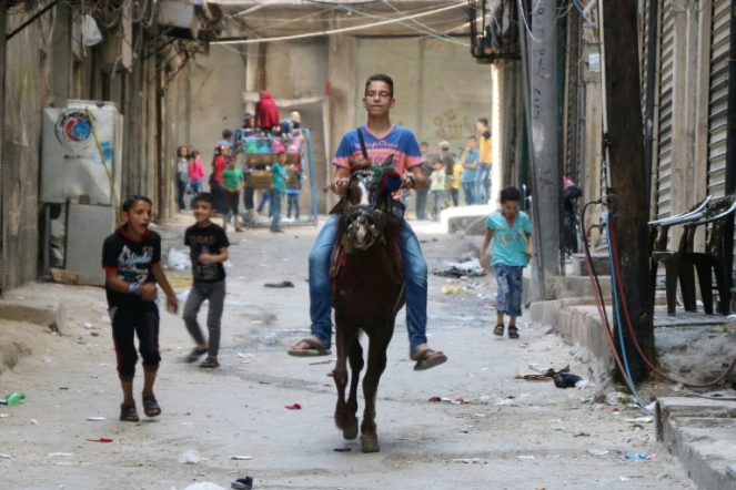 Un garçon syrien monte un cheval dans les rues d'Alep et des enfants jouent lors de l'Aïd au premier jour de la trêve, le 13 esptembre 2016