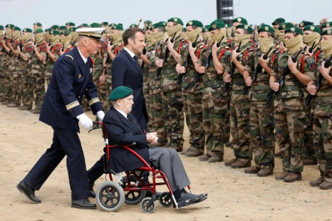 Le président français Emmanuel Macron (d) et le vétéran français de la Seconde guerre mondiale du commando Kieffer Léon Gautier (C) lors d'une cénérmonie de remise de béret vert aux nouveaux fusilliers marins promus à Colleville-Montgomery, dans le Calvados, le 6 juin 2023