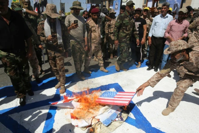 Sur cette photo d'archive, des combattants chiites irakiens des brigades du Hezbollah brûlent des drapeaux américains et israéliens durant un défilé militaire à Bagdad, le 31 mai 2019
