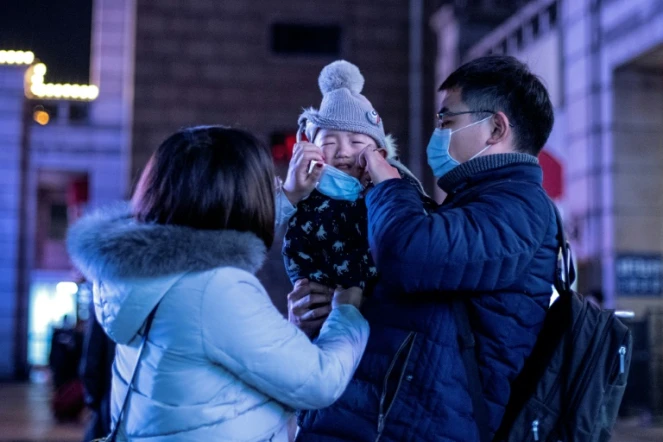 En Chine, des parents mettent un masque protecteur à leur bébé à Pékin, le 23 janvier 2020 