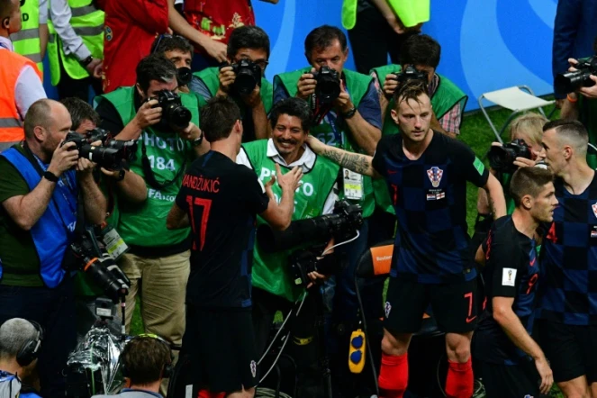L'attaquant croate Mario Mandzukic (g) serre la main du photographe de l'AFP Yuri Cortez (c) qui a été pris sous une mêlée de joueurs croates qui fêtaient un but en demi-finale du Mondial contre l'Angleterre, le 11 juillet 2018 à Moscou 