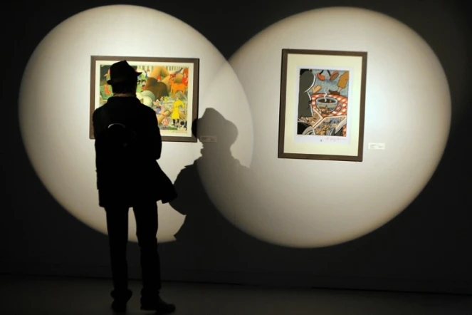 Un homme regarde des dessins d'auteurs américains de comics lors du festival de BD d'Angoulême le 26 janvier 2012