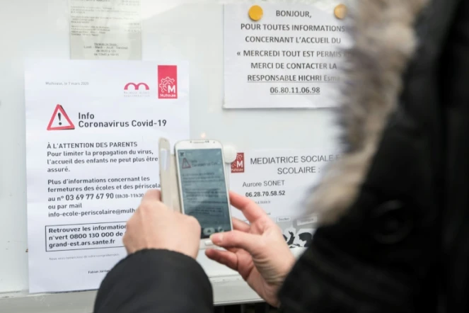 Une femme regarde un panneau d'information sur le coronavirus à Mulhouse à l'entrée d'une école, le 6 mars 2020