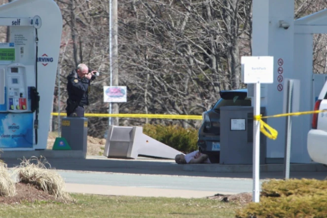 Un membre de la police fédérale de Nouvelle-Ecosse photographie le corps d'un homme abattu à l'issue d'une tuerie qui a fait 17 morts au total, samedi et dimanche en Nouvelle-Ecosse. Photo prise le 19 avril 2020 près de Elmsdale (Nouvelle-Ecosse)