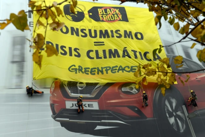 Des militants de Greenpeace ont déployé sur la façade d'un immeuble le 29 novembre 2019 à Madrid une énorme banderole : "Consumérisme=Crise climatique"