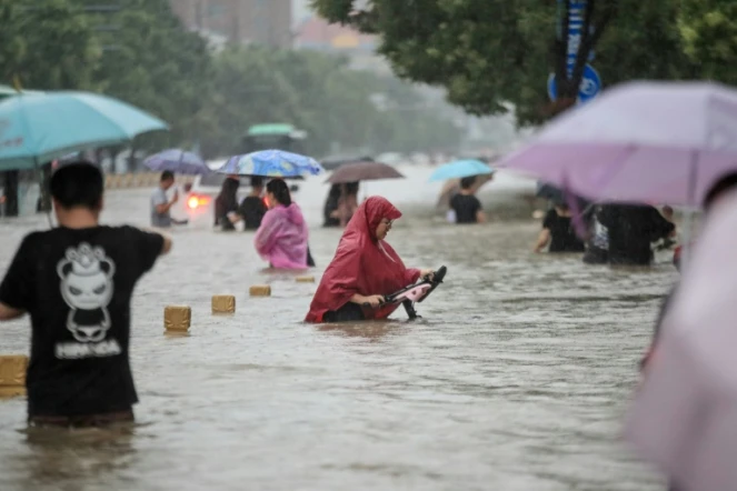 Des habitants de Zhengzhou (Chine) dans une rue de la ville envahie par les eaux, le 20 juillet 2021 