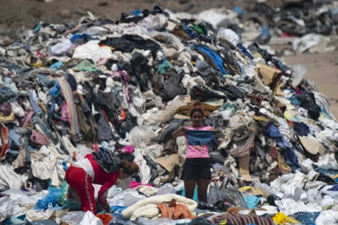 Des personnes cherchent des vêtements usagés dans une décharge sauvage à Alto Hospicio, au Chili, le 26 septembre 2021