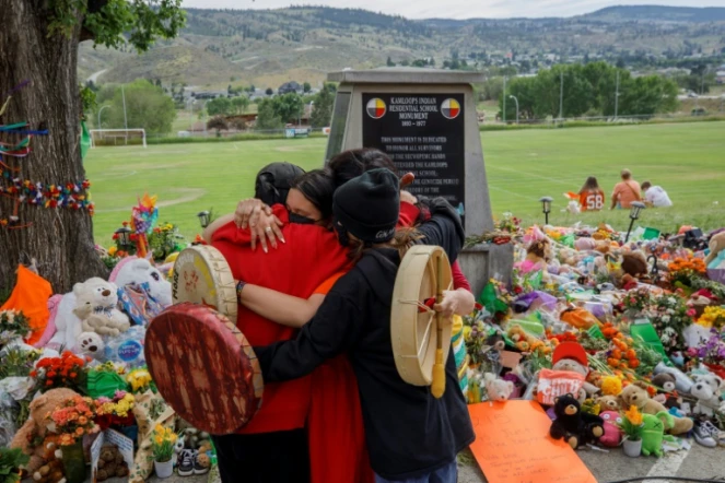 Des membres de la nation Mosakahiken Cree s'enlacent devant un mémorial aux 215 enfants autochtones dont les restes ont été trouvés près d'un pensionnat, le 4 juin 2021 à Kamloops, au Canada
