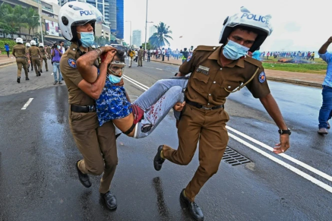 Des policiers emmènent un blessé devant la présidence srilankaise, à Colombo le 9 mai 2022