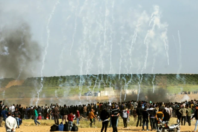 Des Palestiniens courent pour éviter des gaz lacrymogènes tirés par l'armée israélienne près de la frontière entre la bande de Gaza et Israël, le 30 mars 2018