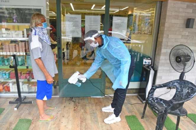 Un employé désinfecte les pieds d'un client avant qu'il entre dans un salon de coiffure, le 28 juin 2020 à Bombay, en Inde