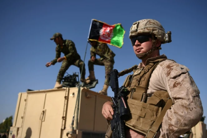 Des soldats afghans hissent le drapeau national près d'un Marine américain  à la base militaire de Lashkar Gah, dans la province du Helmand, le 28 août 2017