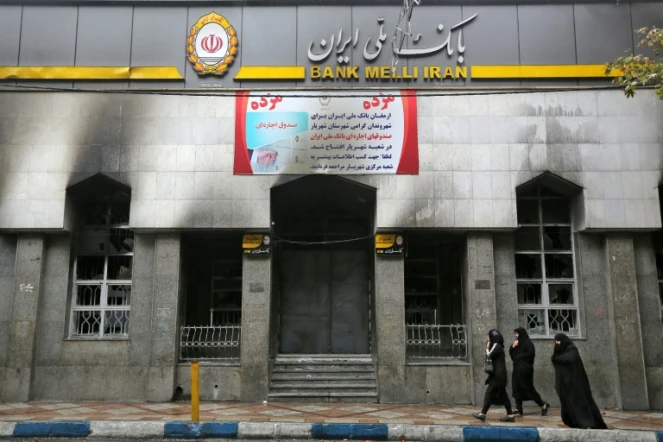 Des Iraniennes marchent devant une banque locale vandalisée durant les manifestations, à Chahriar, en banlieue ouest de Téhéran, le 20 novembre 2019