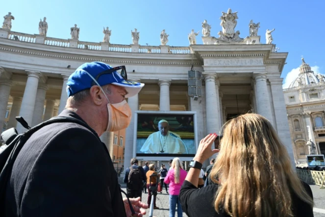 Un couple prend une photo du pape prononçant la prière dominicale depuis sa bibliothèque privée, et retransmise sur des écrans géants sur la plce Saint-Pierre de Rome, le 8 mars 2020, en raison de l'épidémie du nouveau coronavirus