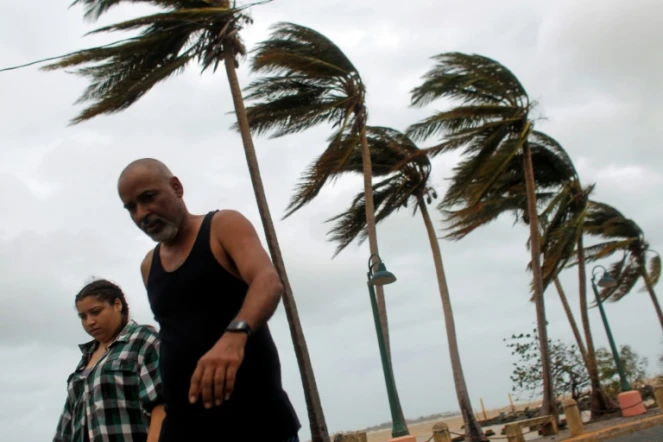 A couple walks through a debris-covered road in Fajardo, Puerto Rico