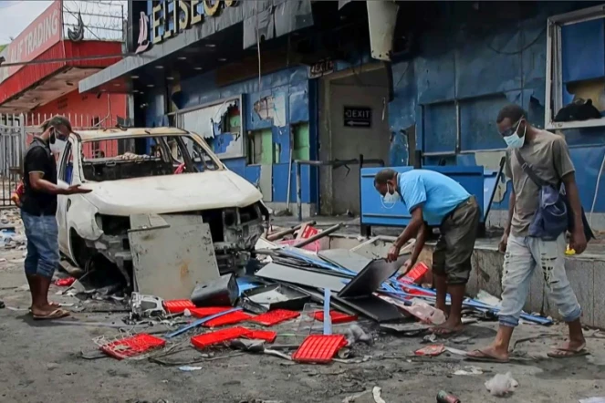 Image tirée d'une vidéo de l'AFPTV montrant des habitants déblayant des débris dans une rue de Port Moresby après des émeutes, le 11 janvier 2024 en Papouasie-Nouvelle-Guinée 
