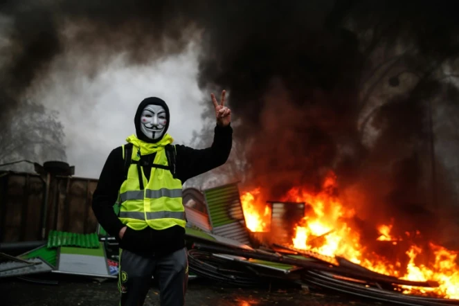 Un manifestant portant un gilet jaune et un masque près d'une barricade en feu, à Paris le 1er décembre 2018
