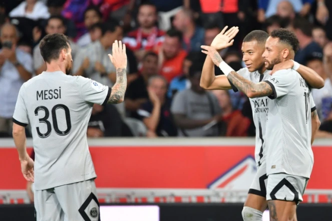 L'attaquant français du Paris SG Kylian Mbappé célèbre un but avec l'attaquant argentin Lionel Messi (à gauche) et l'attaquant brésilien Neymar (tout à droite) lors d'un match de Ligue 1 contre Lille au Stade Pierre-Mauroy de Villeneuve-d'Ascq, le 21 août 2022.