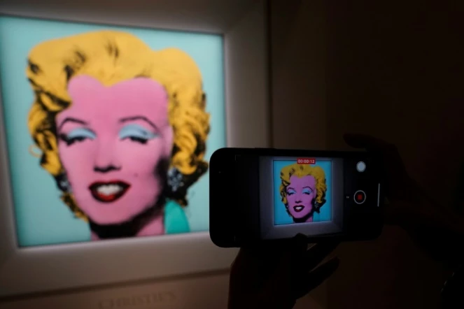 Au siège de la maison d'enchères Christie's à New York le 21 mars 2022, un journaliste photographie le portrait de Marilyn Monroe "Shot Sage Blue Marilyn" par Andy Warhol, estimé à 200 millions de dollars