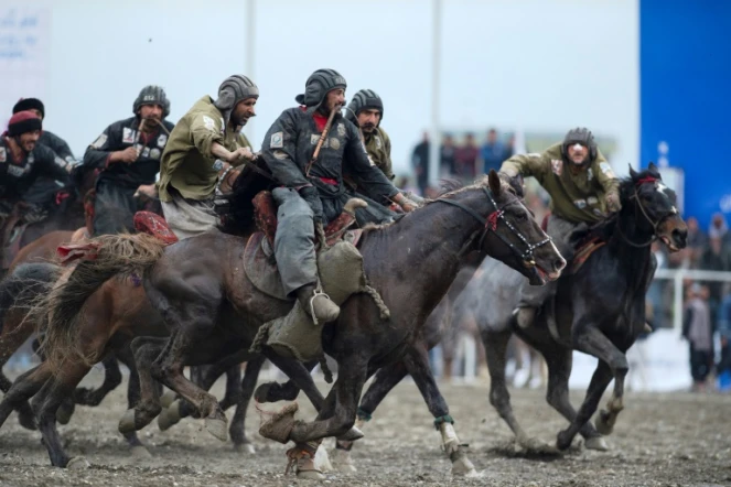 Des cavaliers des équipes de Kandahar (en noir) et Kunduz s'affrontent lors du championnat de bouzkachi à Kaboul, le 6 mars 2022