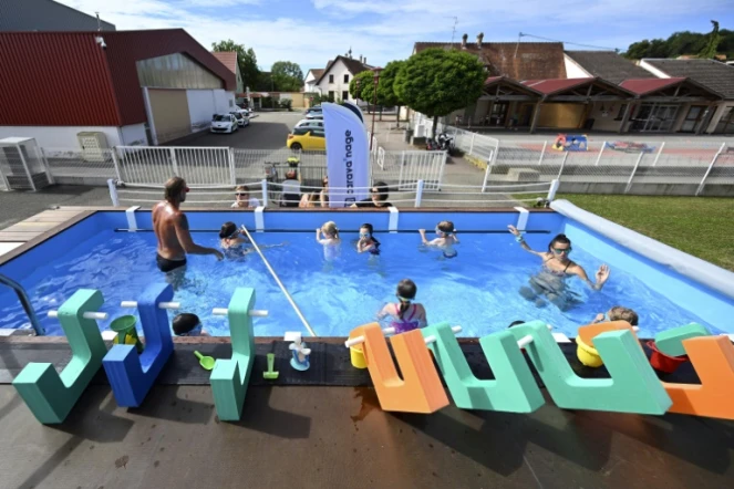 Des enfants prennent une leçon de natation dans une piscine itinérante fabriquée dans un ancien container, le 13 juillet 2022 à Hangenbieten, dans le Bas-Rhin
