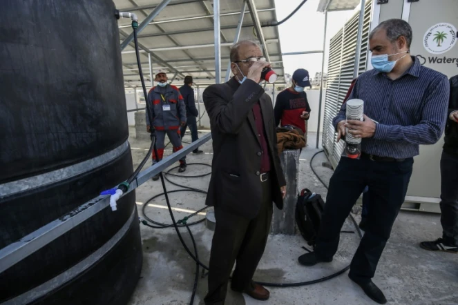 Un ingénieur boit de l'eau produite par un appareil retirant l'humidité de l'air, à Khan Younès (Gaza) le 16 novembre 2020