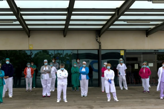 Des personnels de santé observent trois minutes de silence en mémoire des victimes du Covid-19 devant l'hôpital La Fe de Valence, le 19 avril 2020