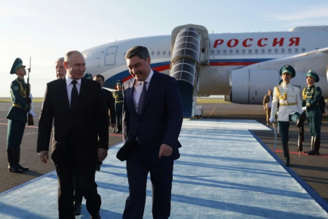 Le président russe Vladimir Poutine (g) accueilli par le Premier ministre kazakh Olzhas Bektenov à son arrivée à l'aéroport d'Astana, le 3 juillet 2024