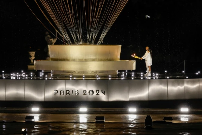 Les porteurs de la flamme olympique Marie-José Pérec et Teddy Rinner enflamment la vasque olympique lors de la cérémonie d'ouverture des JO-2024 à Paris le 26 juillet 2024.