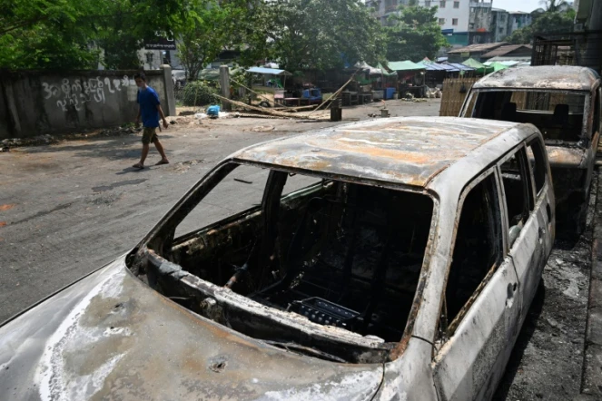 Des véhicules incendiés dans une rue de Rangoun en Birmanie le 15 mars 2021 au lendemain de manifestations contre le coup d'Etat militaire durement réprimées