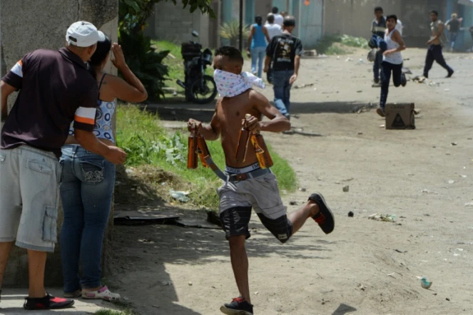 Un pillard s'enfuit avec des bouteilles de bière volées dans un magasin mis à sac à Maracay, le 27 juin 2017.