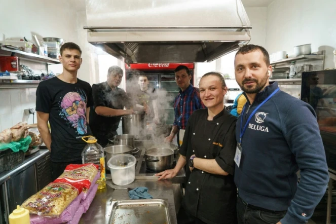 Alexandre Belouga (d) et des bénévoles dans les cuisines de son restaurant où l'on prépare des repas distribués dans les territoires occupés par l'armée russe, le 4 avril 2022 à Zaporijjia, en Ukraine
