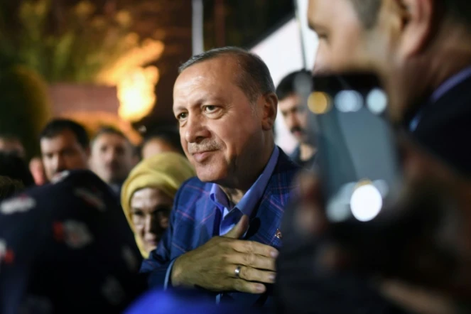 Le président Erdogan (c), accompagné de sa femme Emine, salue ses supporters en sortant du siège du parti AKP, le 16 avril 2017 à Istanbul