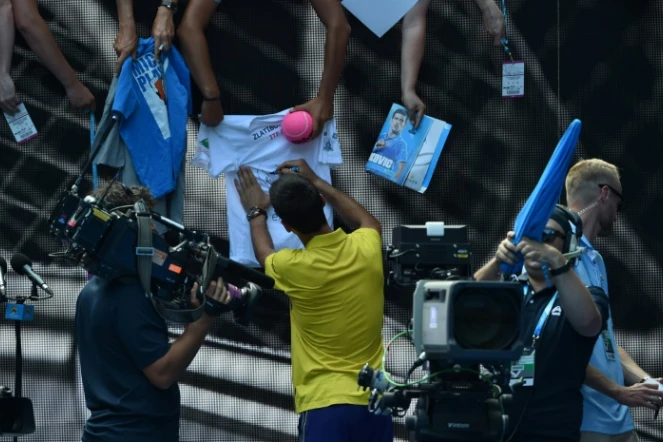 Novak Djokovic signe des autographes après sa victoire face au jeune sud-coréen Chung Hyeon à l'Open d'Australie, le 18 janvier 2016 à Melbourne