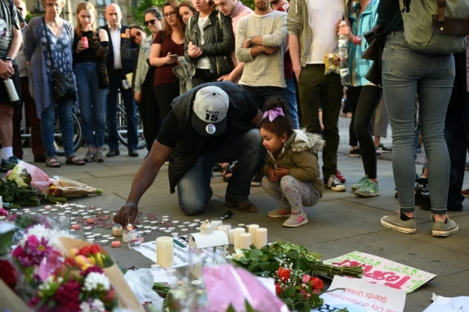 Un homme et sa petite fille allument des bougies à quelques pas du lieu de l'attentat à l'Albert Square de Manchester le 23 mai 2017
