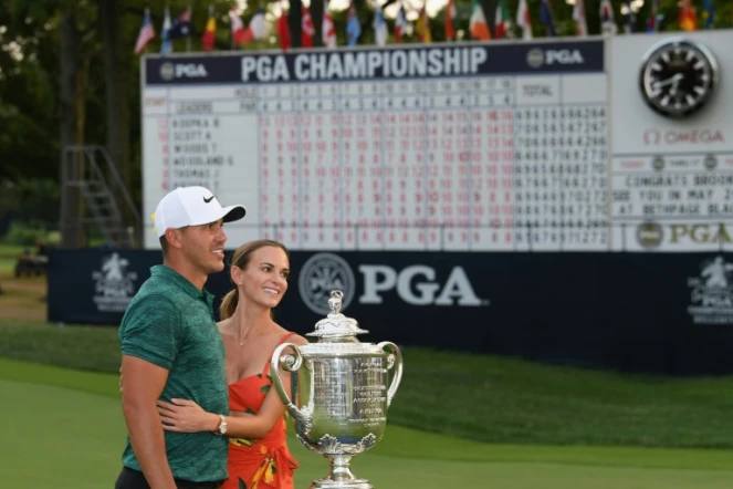 L'Américain Brooks Koepka pose avec sa compagne devant le trophée après sa victoire au Championnat PGA, dernière levée du Grand Chelem, le 12 août 2018 à St Louis (Missouri)