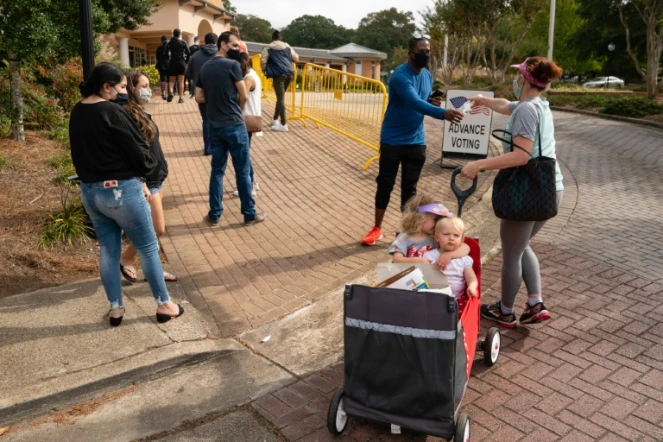 Megan Dominy avec ses deux enfants de quatre et un an, distribue de l'eau et des en-cas aux électeurs qui attendent de pouvoir déposer leurs bulletings lors du vote anticipé pour la présidentielle américaine de 2020, le 24 octobre 2020 à Smyrna