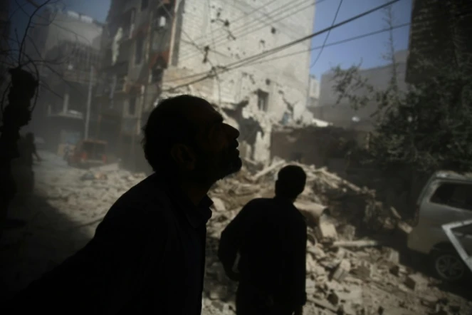Des Syriens regardent les dégâts provoqués par des frappes aériennes sur la zone rebelle de Douma, à l'est de Damas, le 2 octobre 2015