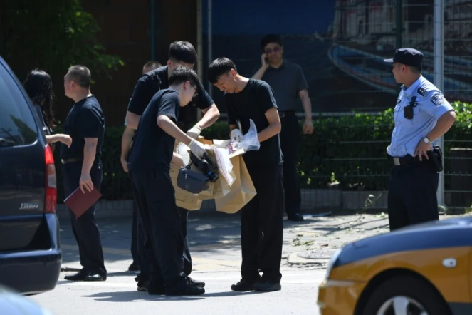 Des agents de sécurité (c) relèvent des indices après une explosion devant l'ambassade des Etats-Unis à Pékin, le 26 juillet 2018