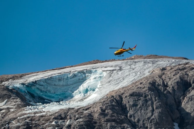 Un hélicoptère de secours survole, le 4 juillet 2022, le glacier qui s'est effondré la veille sur la montagne de Marmolada, en Italie