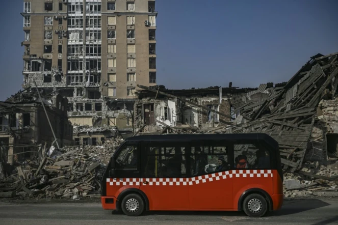 Un minibus passe devant des maisons détruites par un bombardement, le 25 mars 2022 dans un bombardement à Kharkiv, en Ukraines 2022