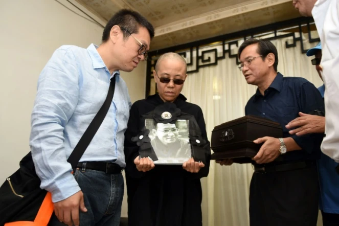 Photographie du Shenyang Municipal Information Office, montrant la femme du dissident chinois Liu Xiaobo, Liu Xia (c) et son frère, Liu Xiaoguang (L), recevant les cendres du défunt après son incinération, le 15 juillet 2015 à Shenyang