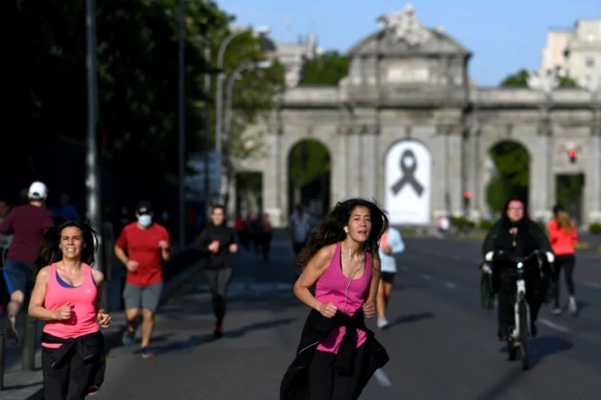 Joggeurs devant la Porte d'Alcala, ornée d'un ruban noir en signe de deuil, le 2 mai 2020 à Madrid