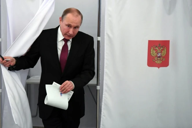 Le président russe Vladimir Poutine sort d'un isoloir lors de la présidentielle russe, le 18 mars 2018 à Moscou